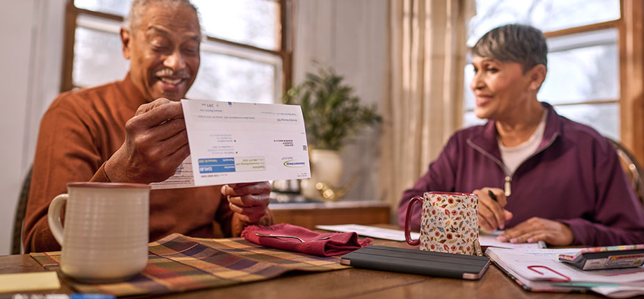 Older couple at kitchen table pleasantly surprised by their Consumers Energy natural gas bill